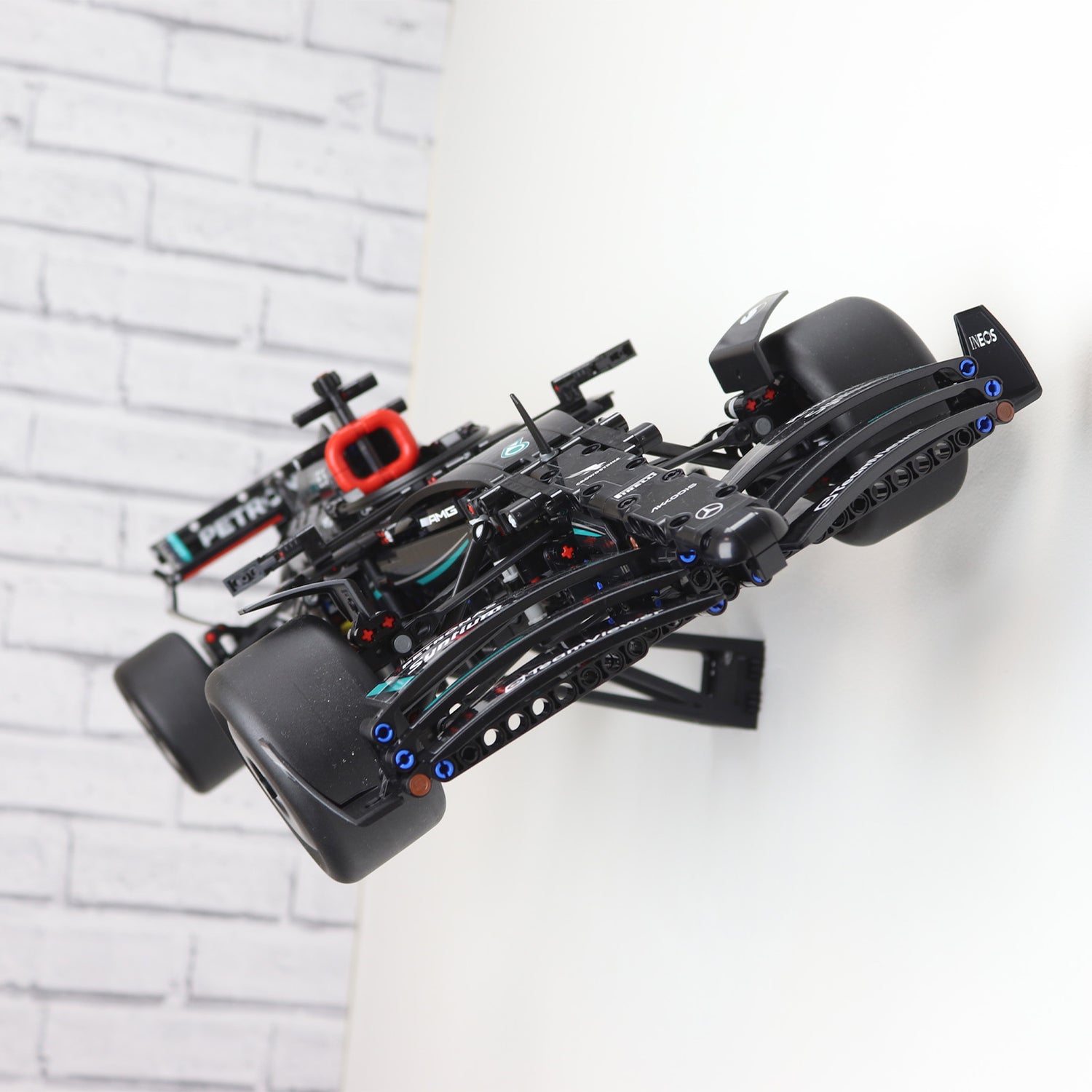 Wall display mount holding LEGO® Technic Mercedes F1 Car (42171) model, showcasing the car at an angled position on the wall for an eye-catching presentation.
