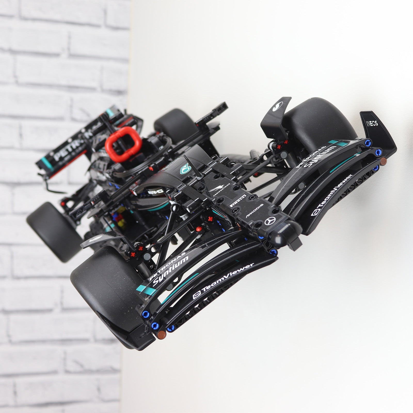 Wall display mount holding LEGO® Technic Mercedes F1 Car (42171) model, showcasing the car at an angled position on the wall for an eye-catching presentation.
